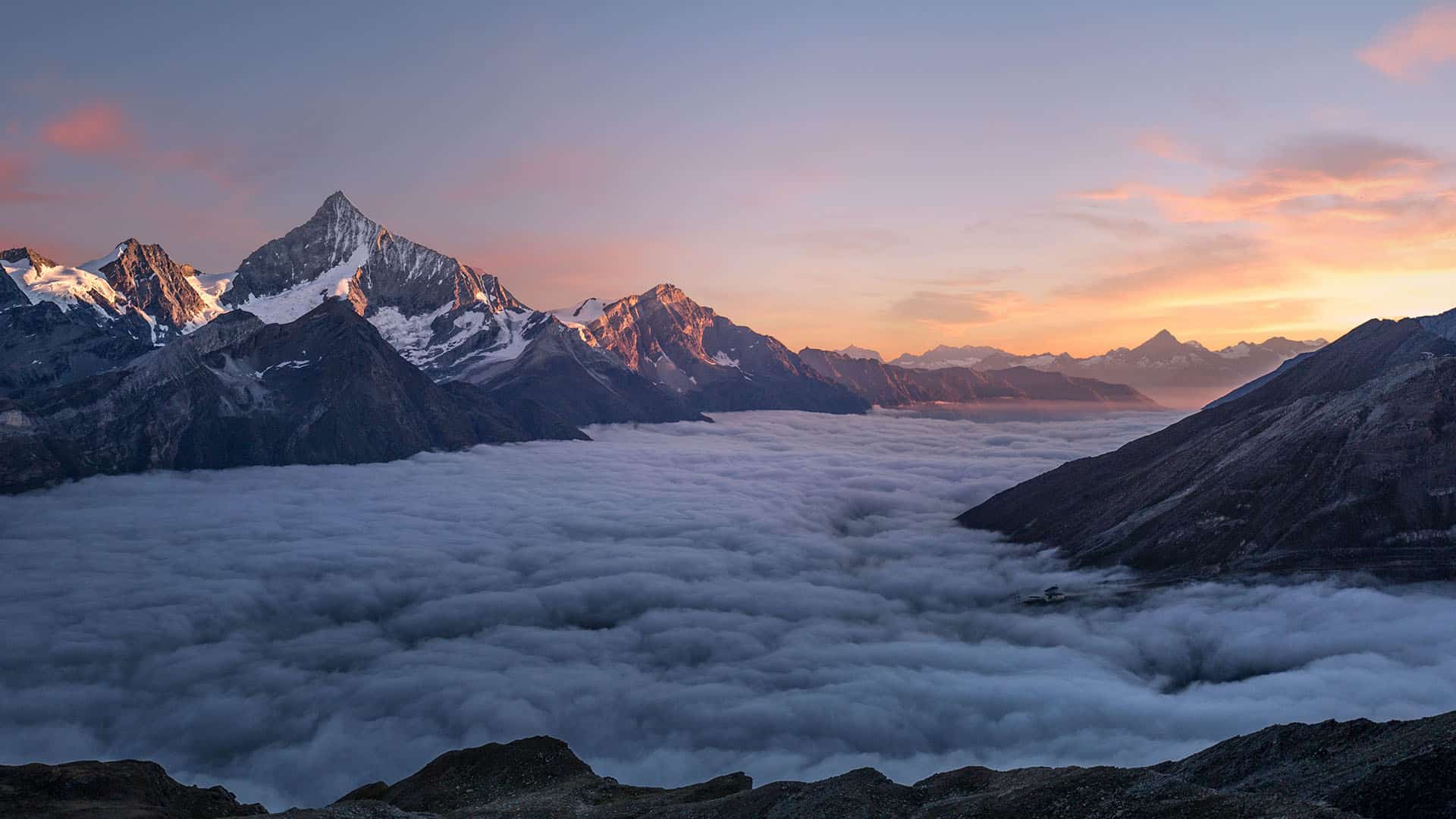 Chaîne montagneuse suisse enneigée au lever du soleil avec mer de nuages
