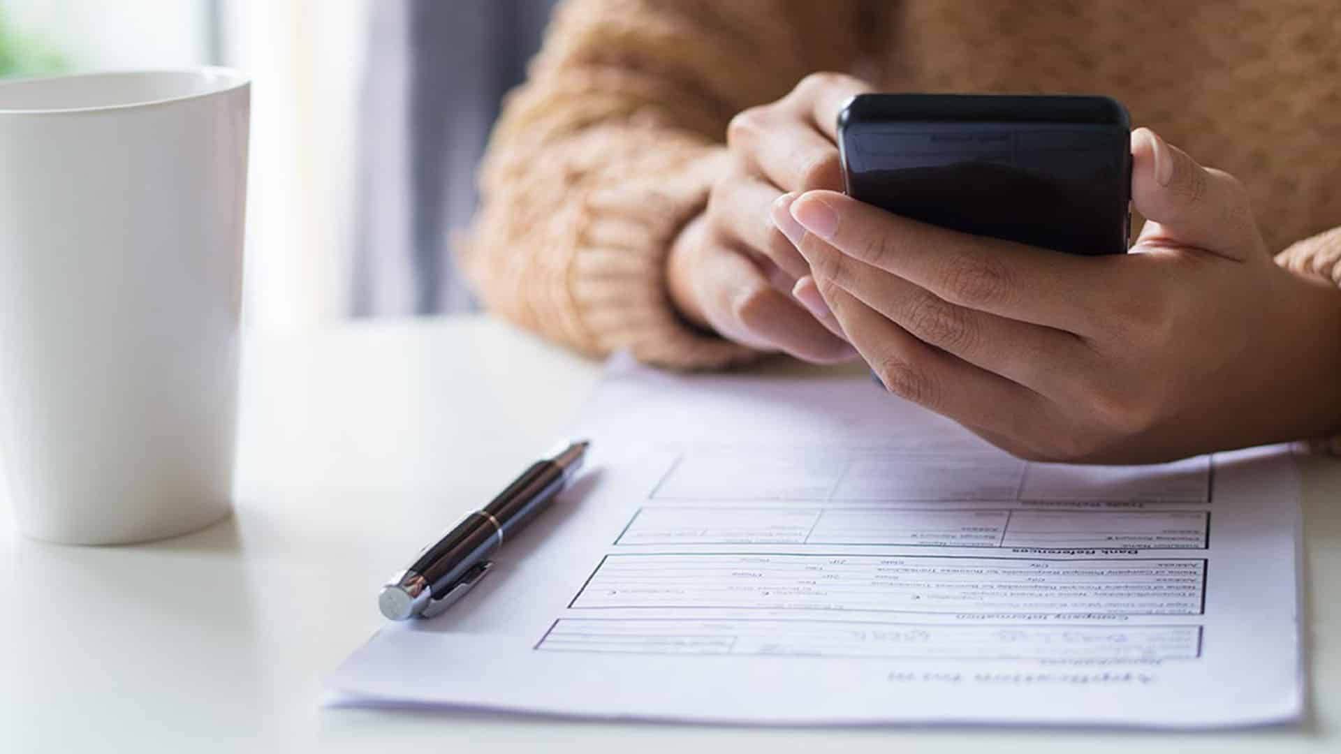 Personne consultant un smartphone pour vérifier des taux de change CHF EUR lors d'une transaction financière