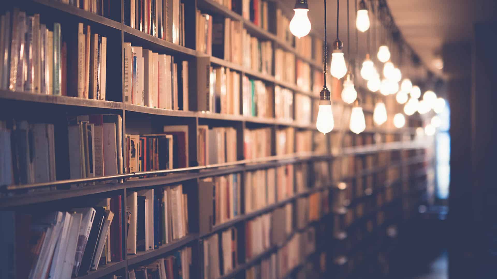 Bibliothèque avec étagères de livres éclairées par des ampoules suspendues