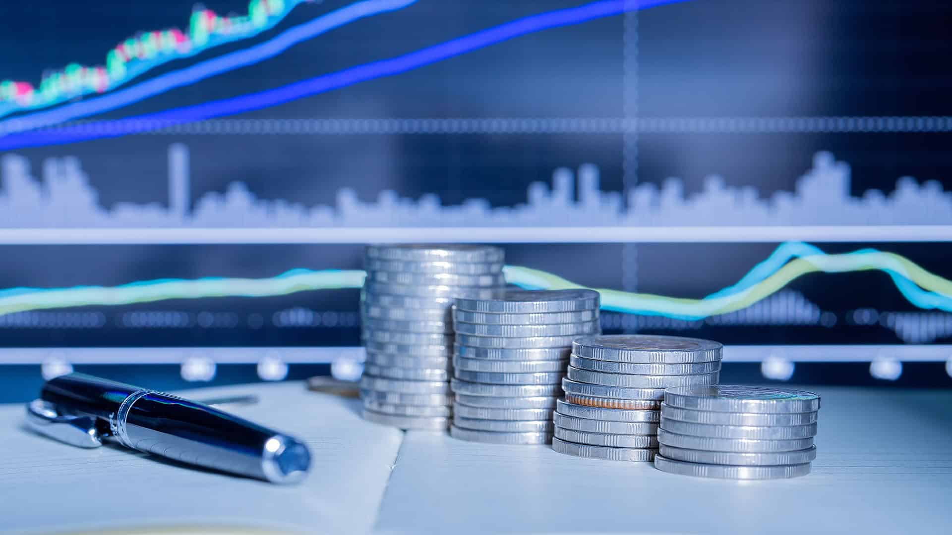 Piles de pièces de monnaie suisses avec graphiques boursiers et stylo sur bureau