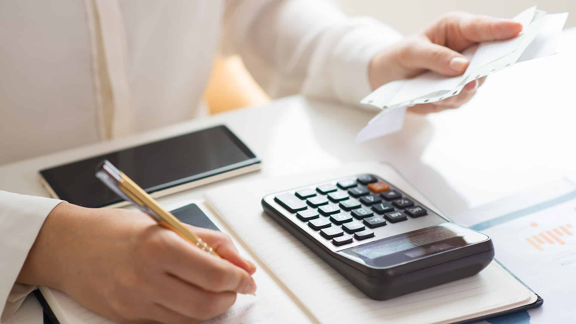 Personne tenant des billets EUR avec calculatrice et smartphone pour convertir CHF EUR