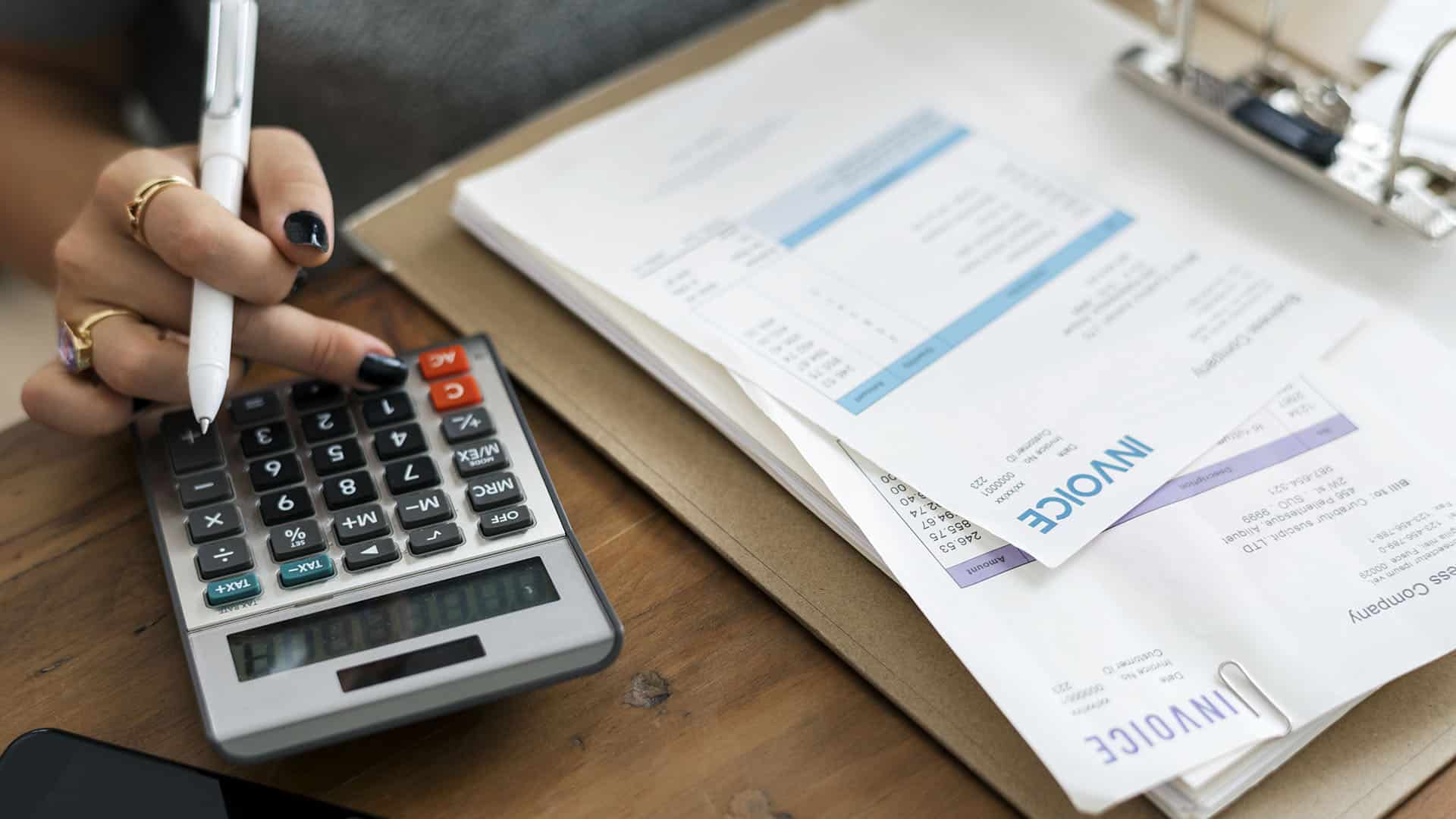 Femme utilisant une calculatrice pour analyser des documents financiers et graphiques de change