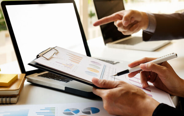 Deux professionnels analysent des graphiques de change CHF/EUR sur documents et ordinateur portable en réunion