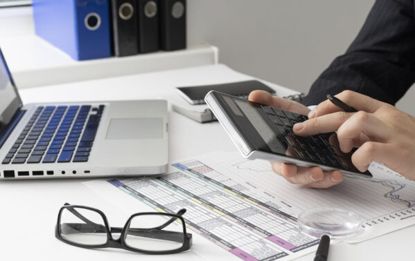 Professionnel calculant des taux de change CHF/EUR avec calculatrice, laptop et documents financiers sur son bureau