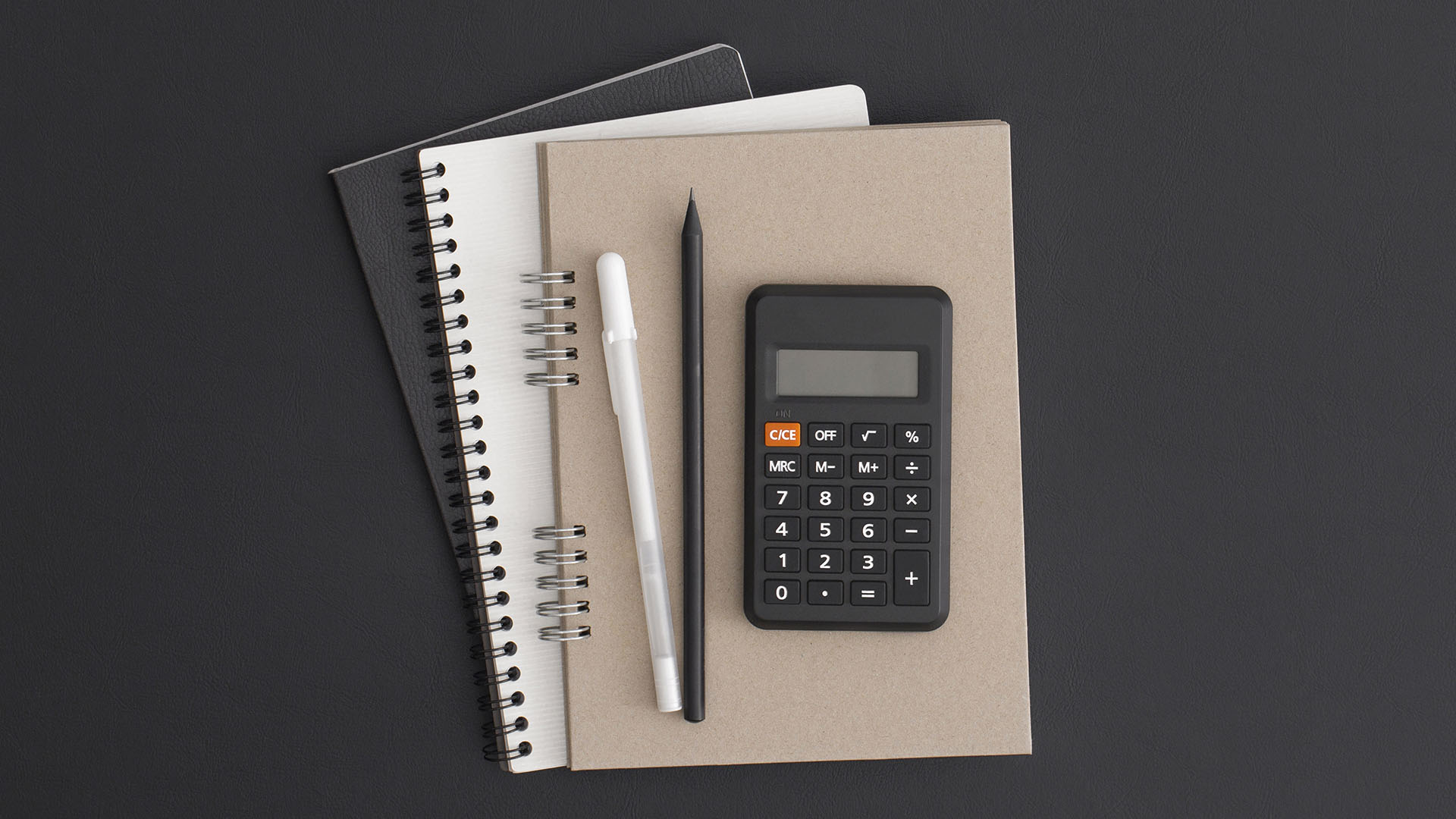 Calculatrice noire sur carnet beige avec stylos et carnets à spirale, symbolisant le calcul de change CHF/EUR