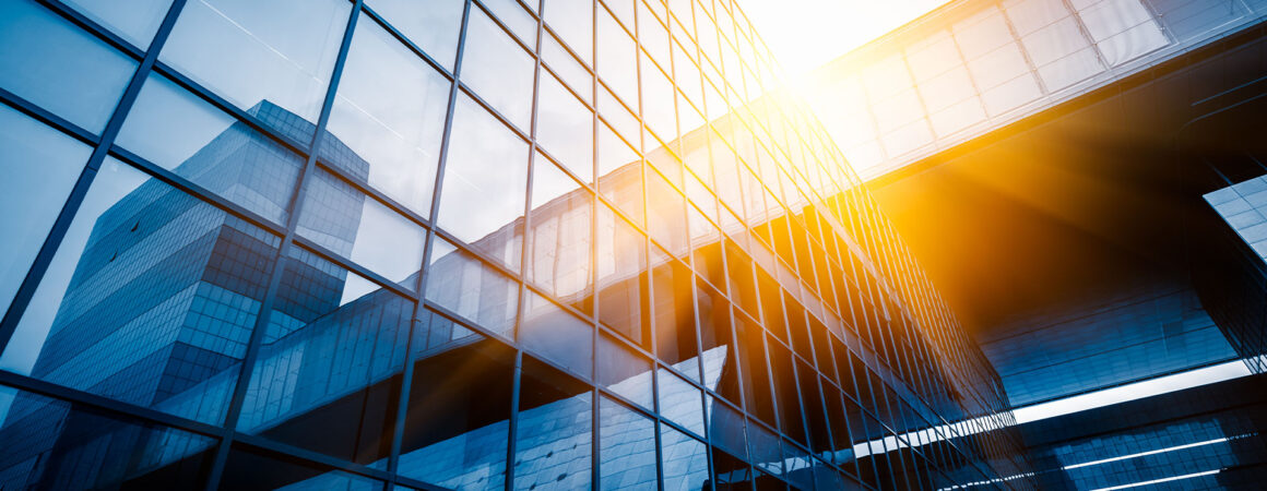 Immeuble de verre moderne avec façade transparente et soleil couchant, symbolisant la finance et le change CHF/EUR