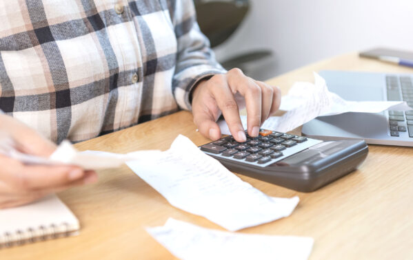 Personne utilisant une calculatrice avec des documents financiers sur un bureau en bois