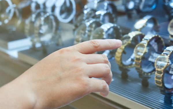 Main pointant vers une vitrine de montres de luxe en or et acier inoxydable