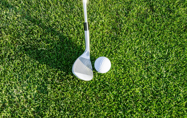 Club de golf et balle blanche sur gazon vert, symbolisant le loisir et le bien-être financier