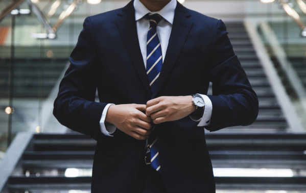 Homme d'affaires en costume bleu marine et cravate rayée dans un cadre professionnel feutré