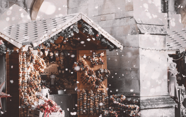 Chalet de marché de Noël alpin décoré de chocolats et ornements dorés sous la neige