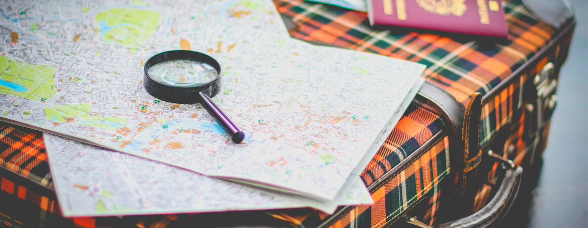 Valise de voyage avec cartes, loupe, passeport et lunettes de soleil pour préparer un voyage