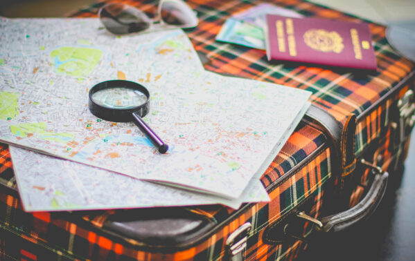 Valise de voyage avec cartes, loupe, passeport et lunettes de soleil pour préparer un voyage