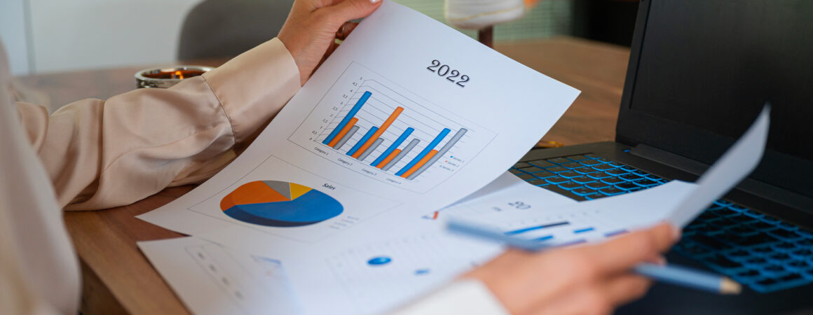 Professionnel consultant analysant des rapports financiers 2022 avec graphiques en barres et camemberts