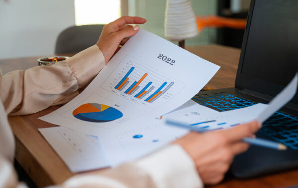 Professionnel consultant analysant des rapports financiers 2022 avec graphiques en barres et camemberts