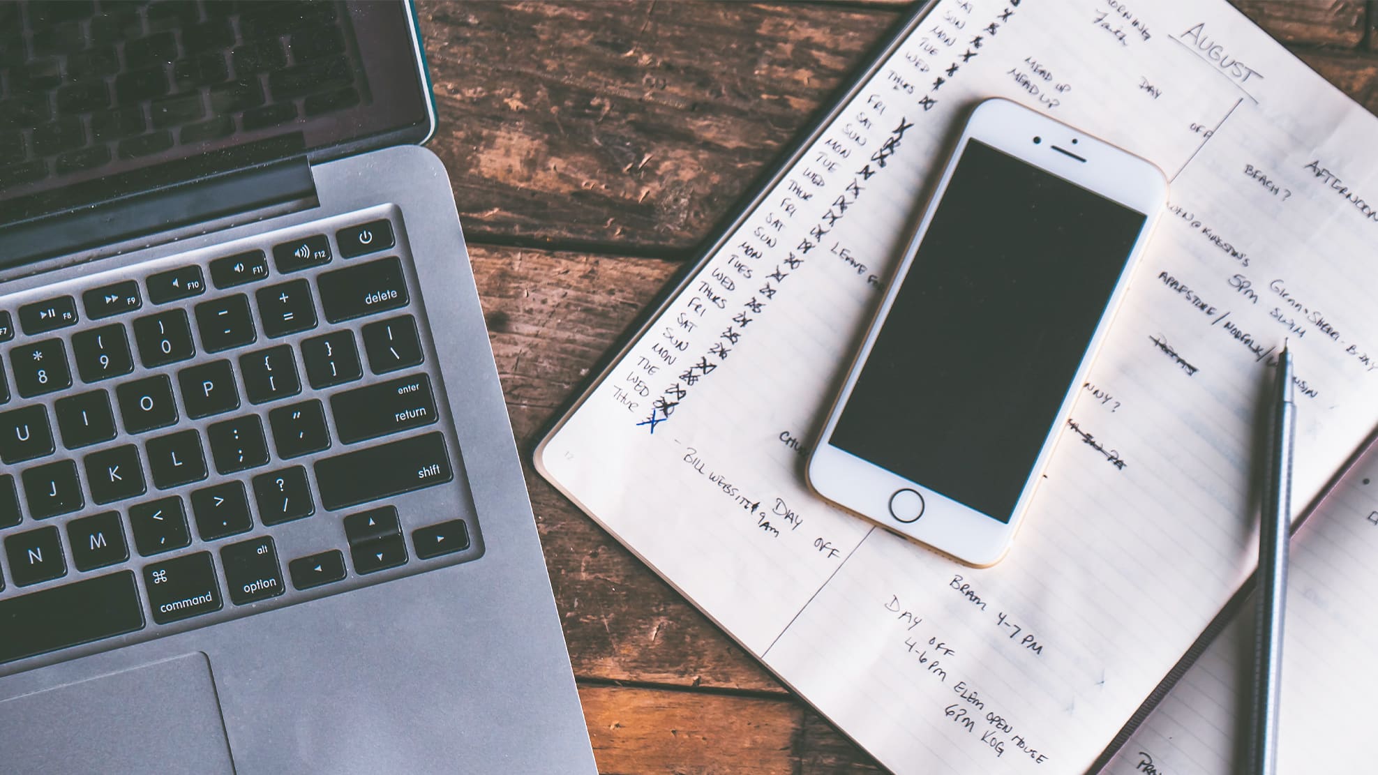 Ordinateur et smartphone blancs avec agenda manuscrit sur bureau en bois — outils de gestion financière CHF/EUR
