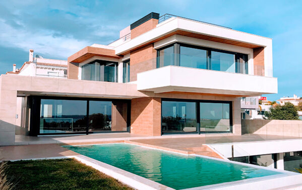 Villa moderne avec façade en brique et blanc, grandes baies vitrées, piscine turquoise, terrasse carrelée et palmiers