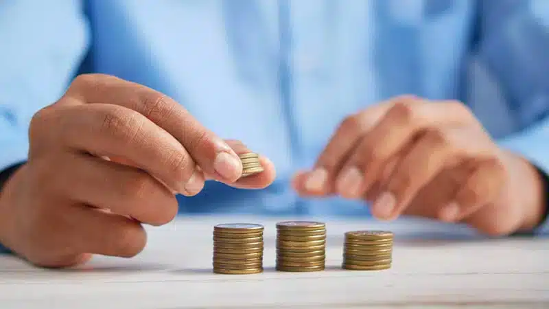 Mains empilant des pièces de monnaie en euros, symbolisant l'épargne et la gestion financière