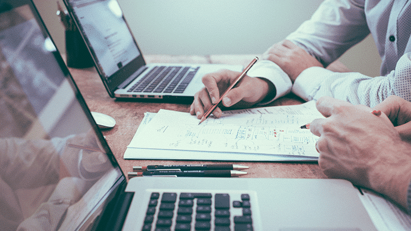 Professionnel en costume remplissant un formulaire de change CHF/EUR avec ordinateur portable