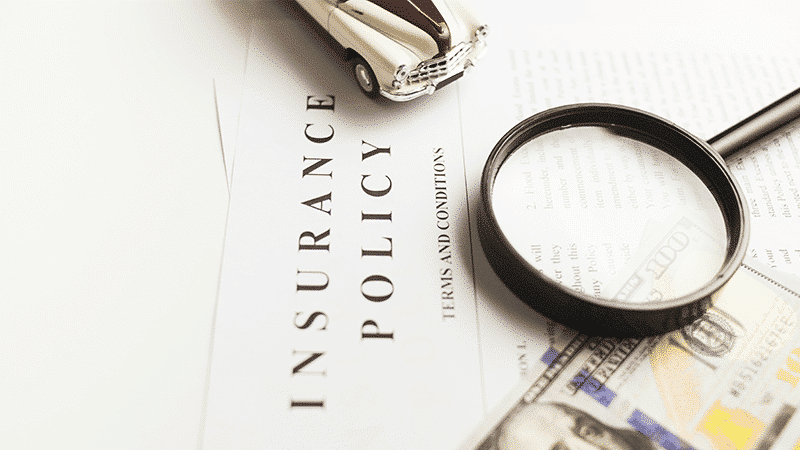 Document d'assurance automobile avec voiture miniature, loupe et billets EUR, symbolisant la couverture d'assurance