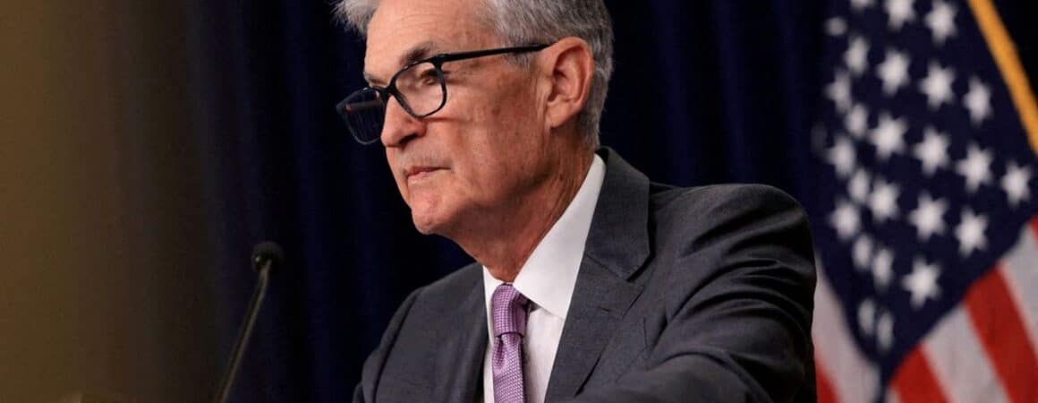 Homme d'affaires senior en costume gris et cravate mauve, portant des lunettes, devant un drapeau américain