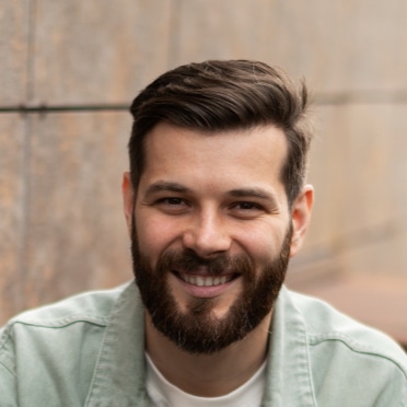 Homme souriant portant une chemise grise clair, représentant un client satisfait de b-sharpe.com
